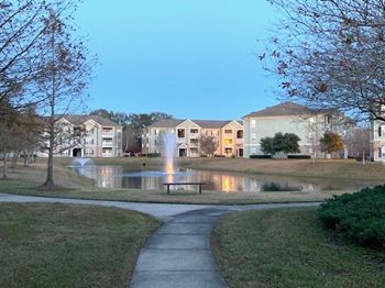 A residential area with a fountain in the middle of a grassy area.